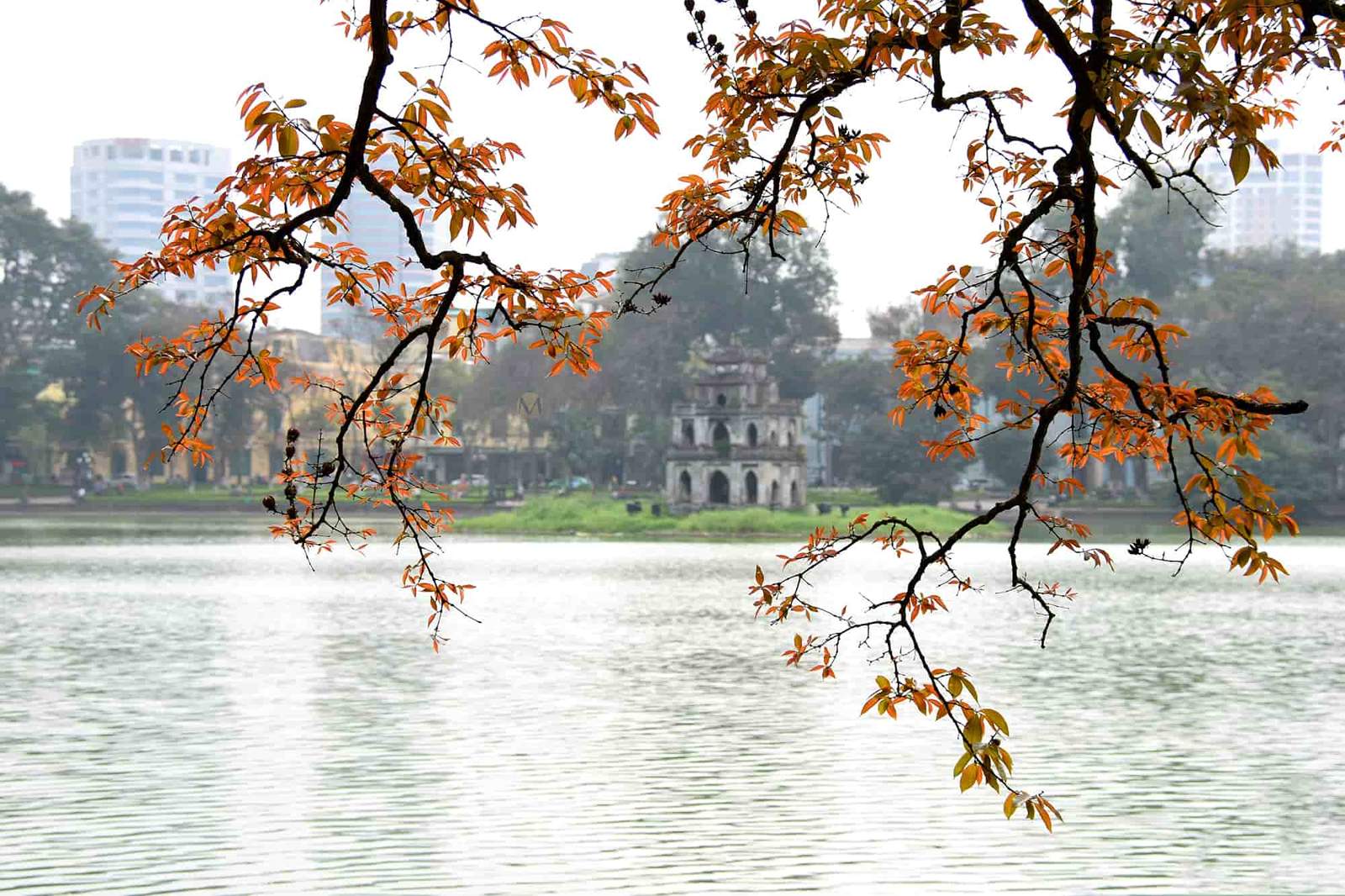 Turtle Tower at Hoan Kiem Lake in Hanoi Vietnam surrounded by trees and calm water