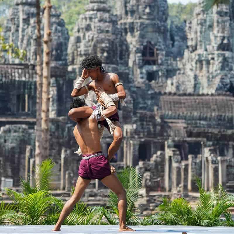 Family enjoying traditional dance performance at Angkor Wat, Cambodia, showcasing cultural heritage.