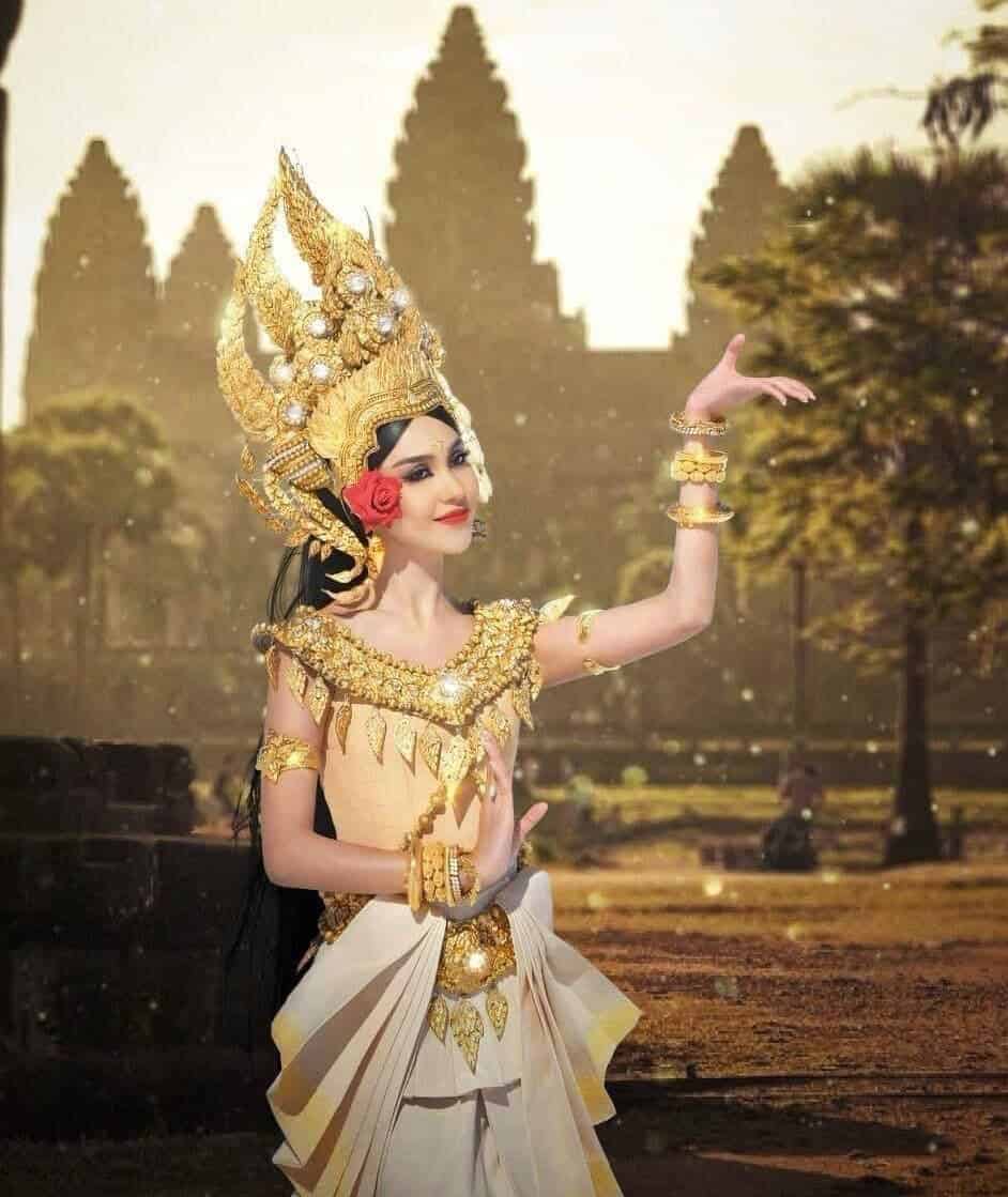 Traditional Thai dancer in elaborate costume performing at historic site.