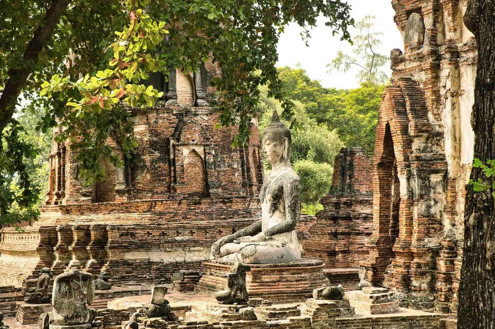 Ancient Buddha statue surrounded by ruins at a historic temple in Thailand. Perfect for cultural tra.