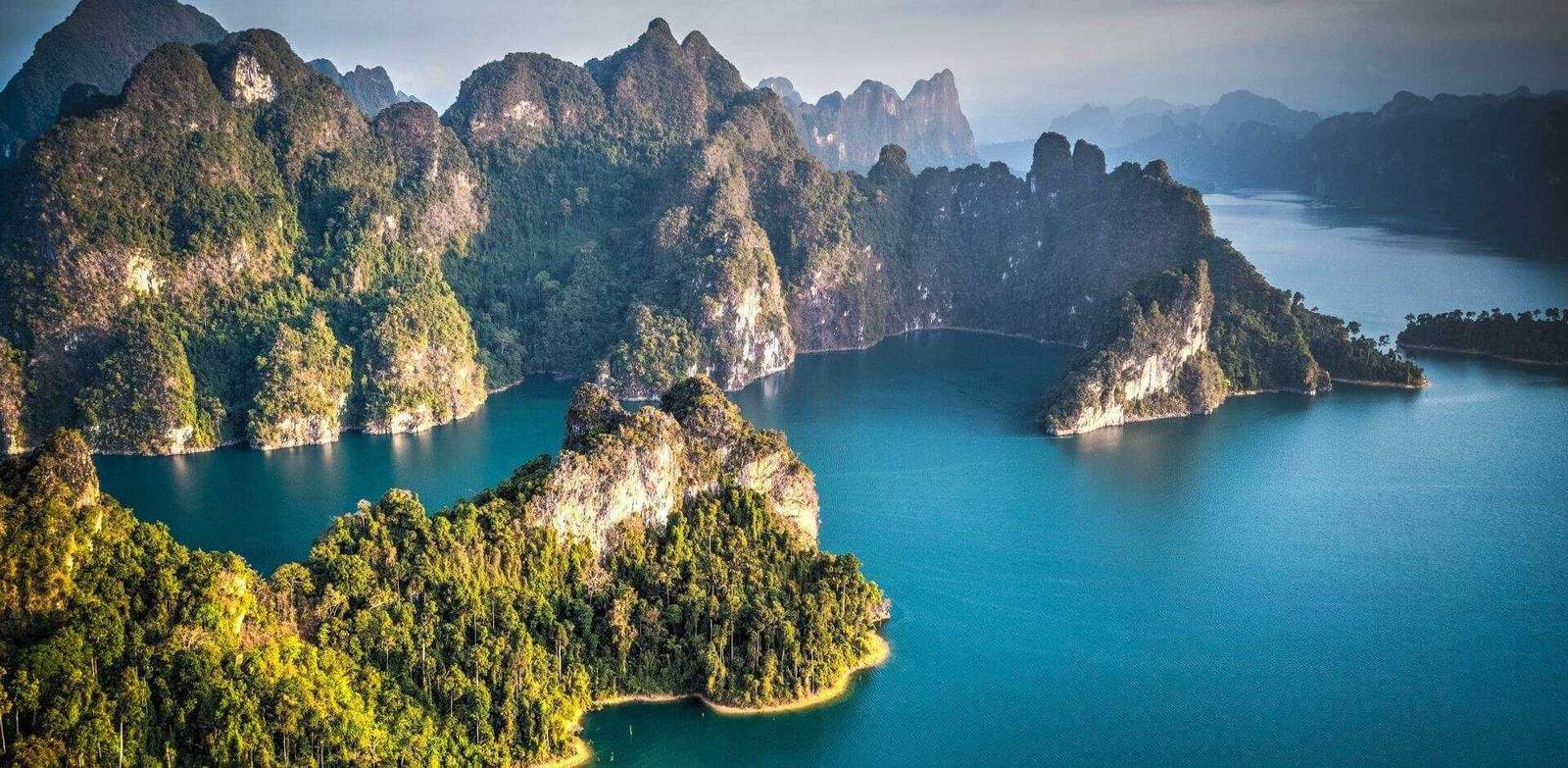 Scenic view of Khao Sok Lake with limestone cliffs and lush greenery in Thailand.