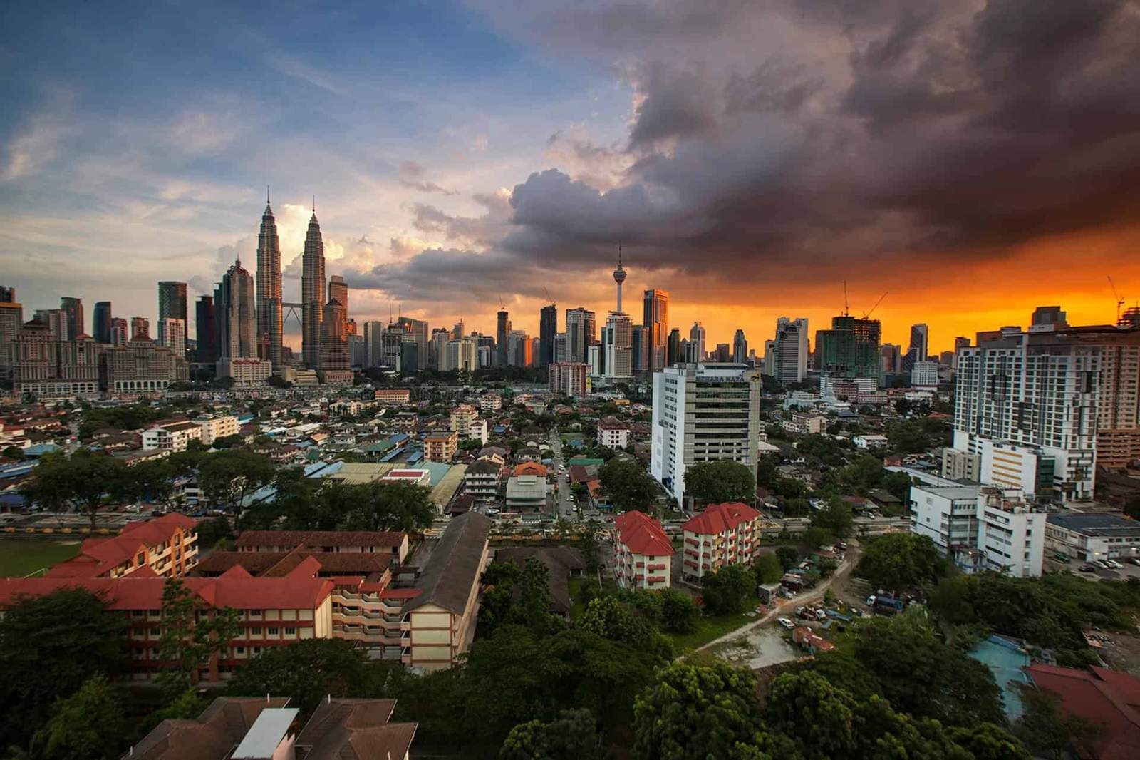 Kuala Lumpur cityscape featuring Petronas Towers and modern skyscrapers at sunset.