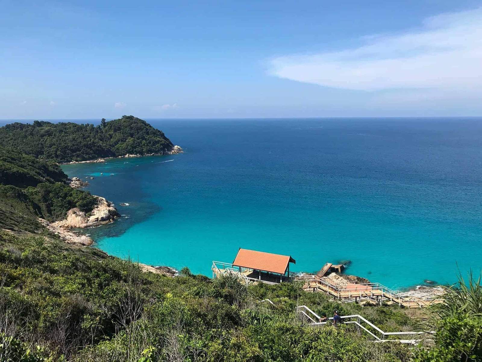 Beautiful tropical coastline with turquoise waters and lush green hills in the background.