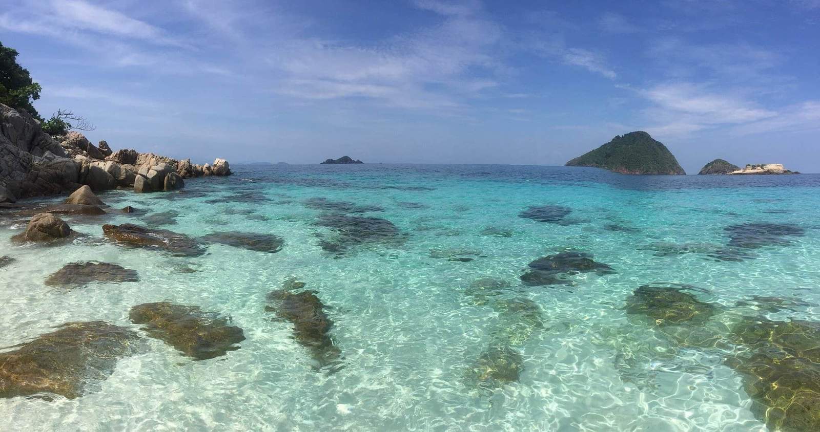 Beautiful tropical beach with turquoise water and rocky shoreline.
