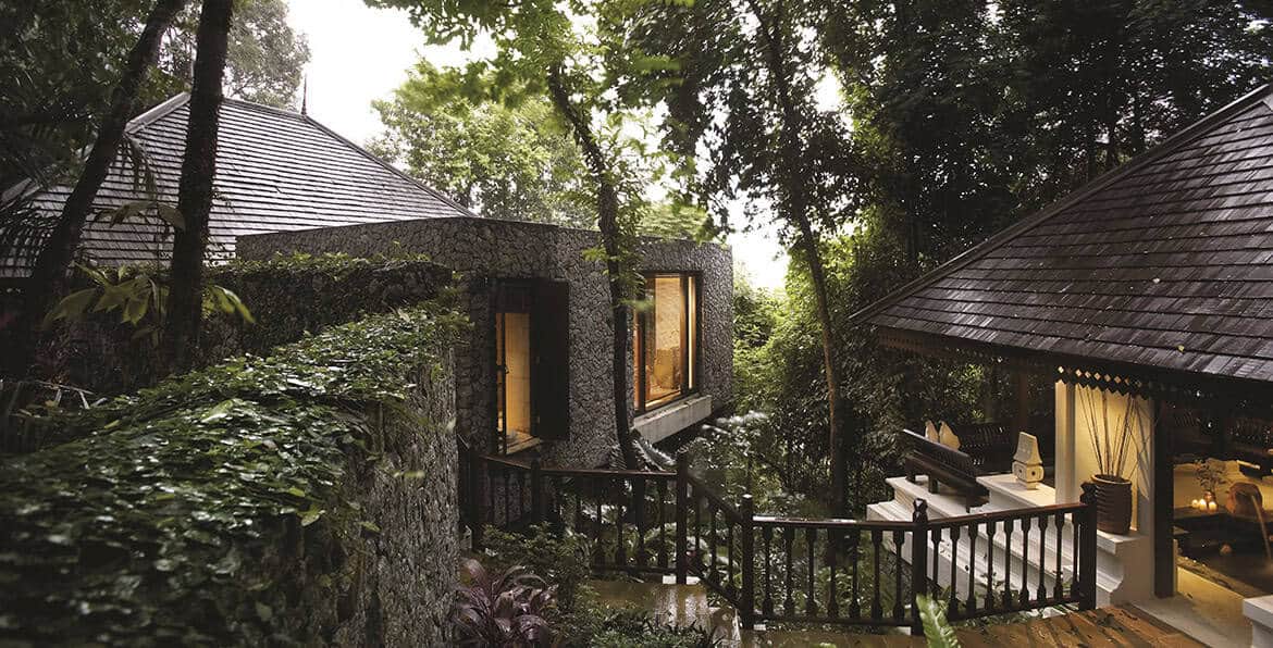 Cozy modern cabin nestled in lush forest with outdoor deck and large windows.
