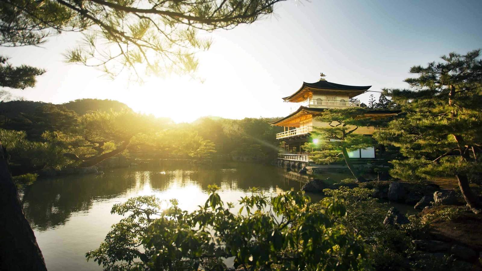 Serene Japanese garden with traditional pagoda at sunset, peaceful water reflection, and lush greene.