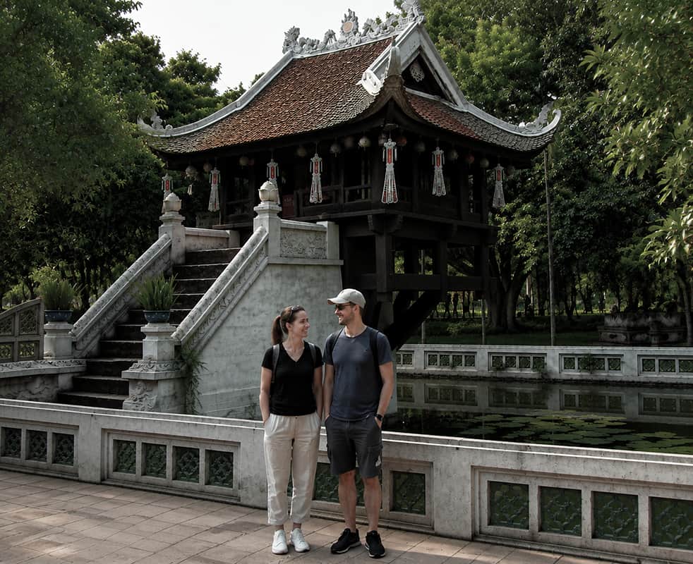 Couple visiting One Pillar Pagoda in Hanoi, Vietnam, a historic Buddhist landmark surrounded by lush greenery