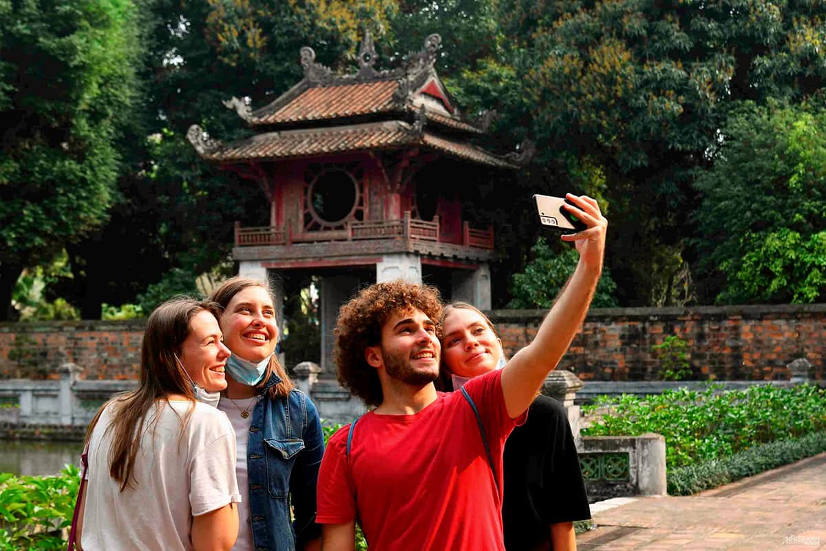 International travelers taking a photo at a historic temple in Hanoi, Vietnam